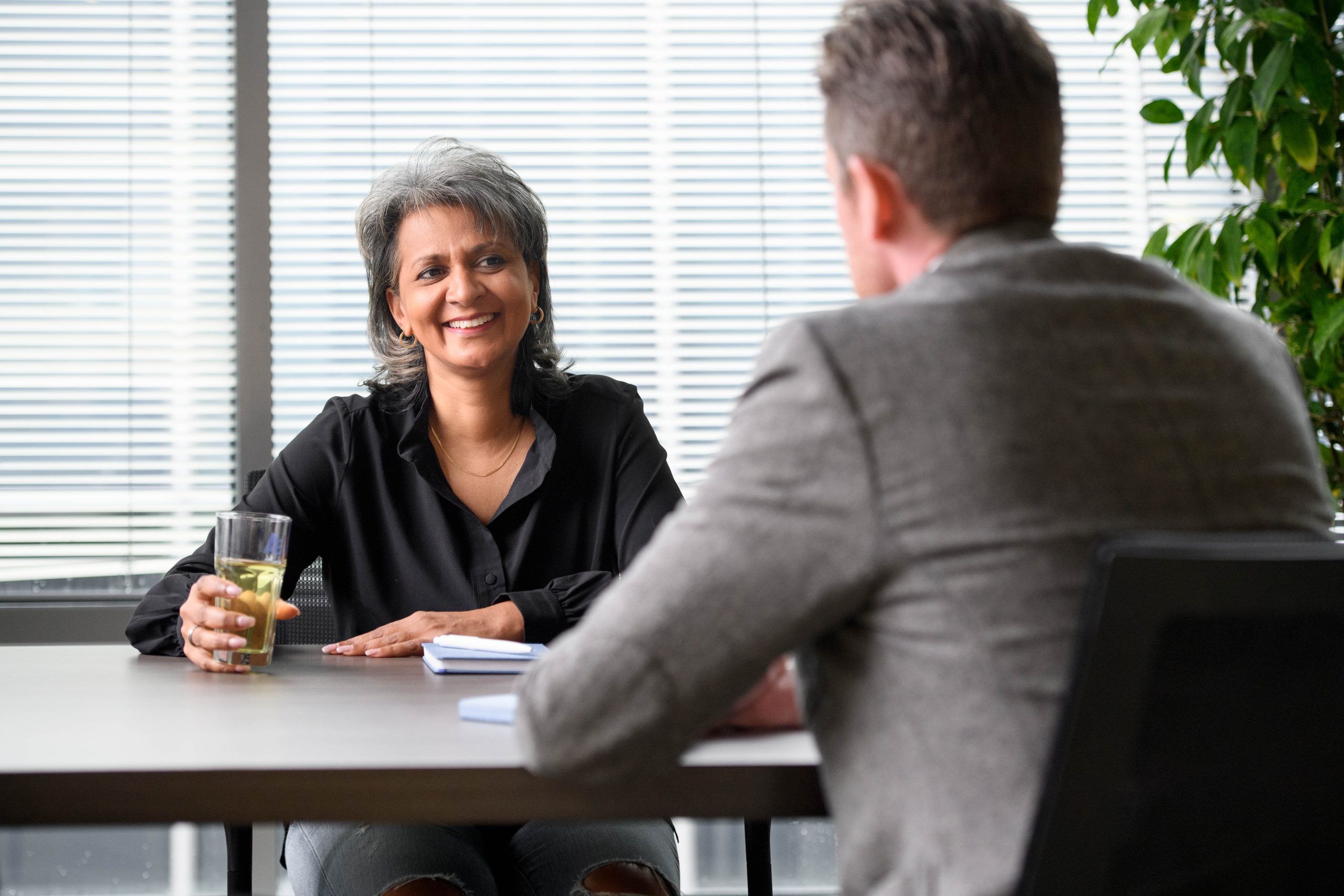 Twee managers zitten aan tafel, met elkaar in gesprek