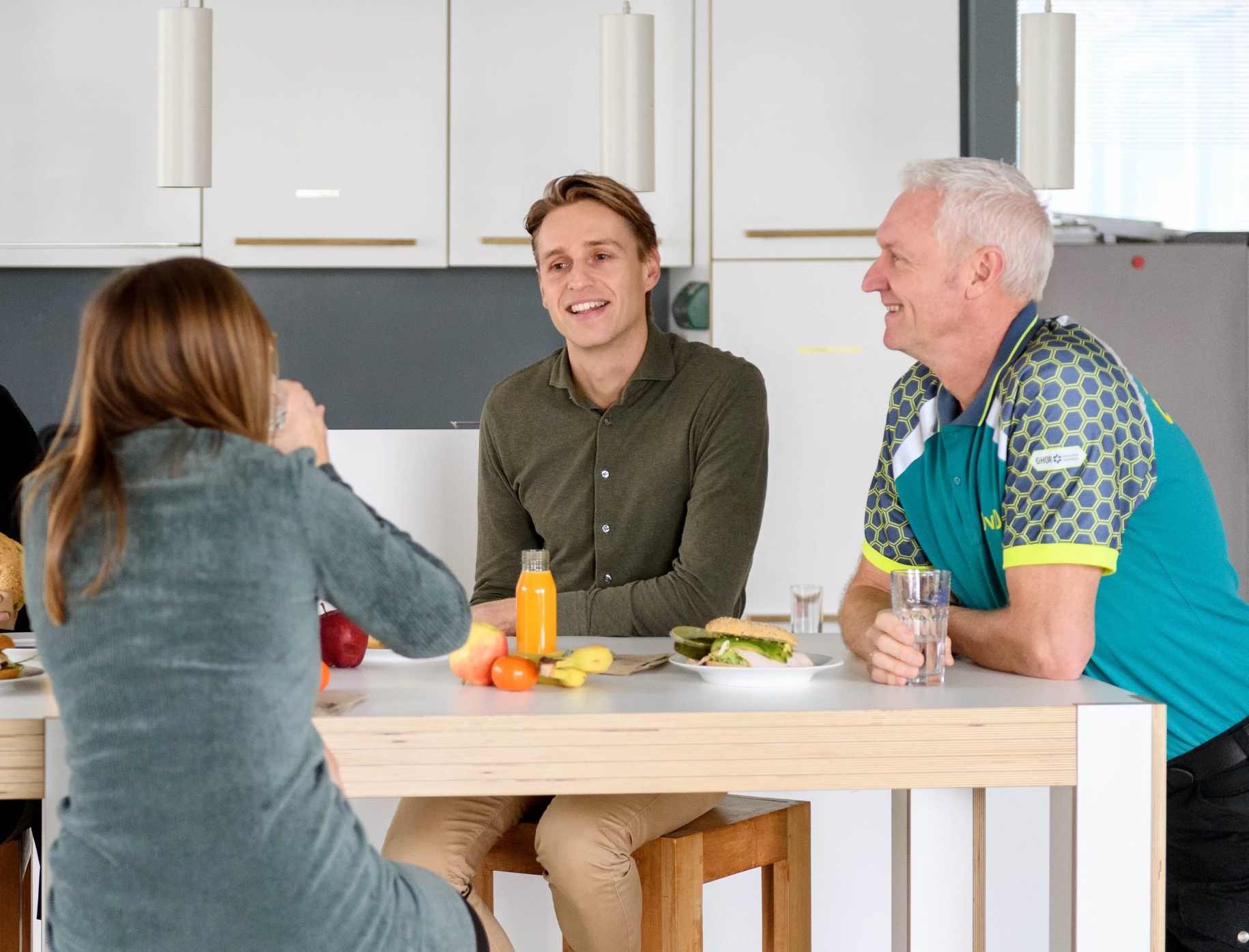 Vier kantoor- en ambulancemedewerkers zijn samen aan het lunchen in de kantine