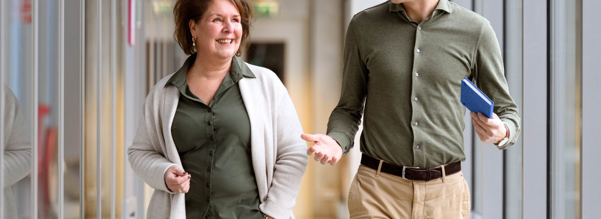 Twee HR-medewerkers lopen pratend met elkaar door de gang