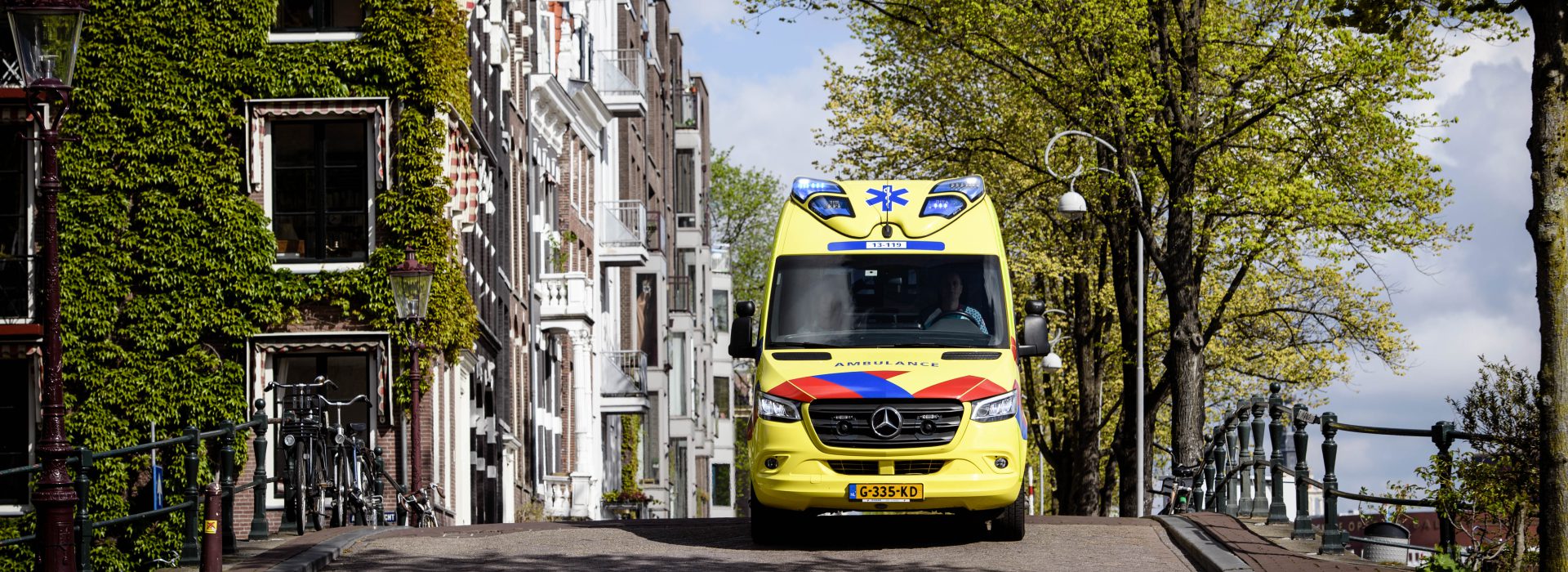 Vooraanzicht van een ambulance die rijdt door een Amsterdamse omgeving