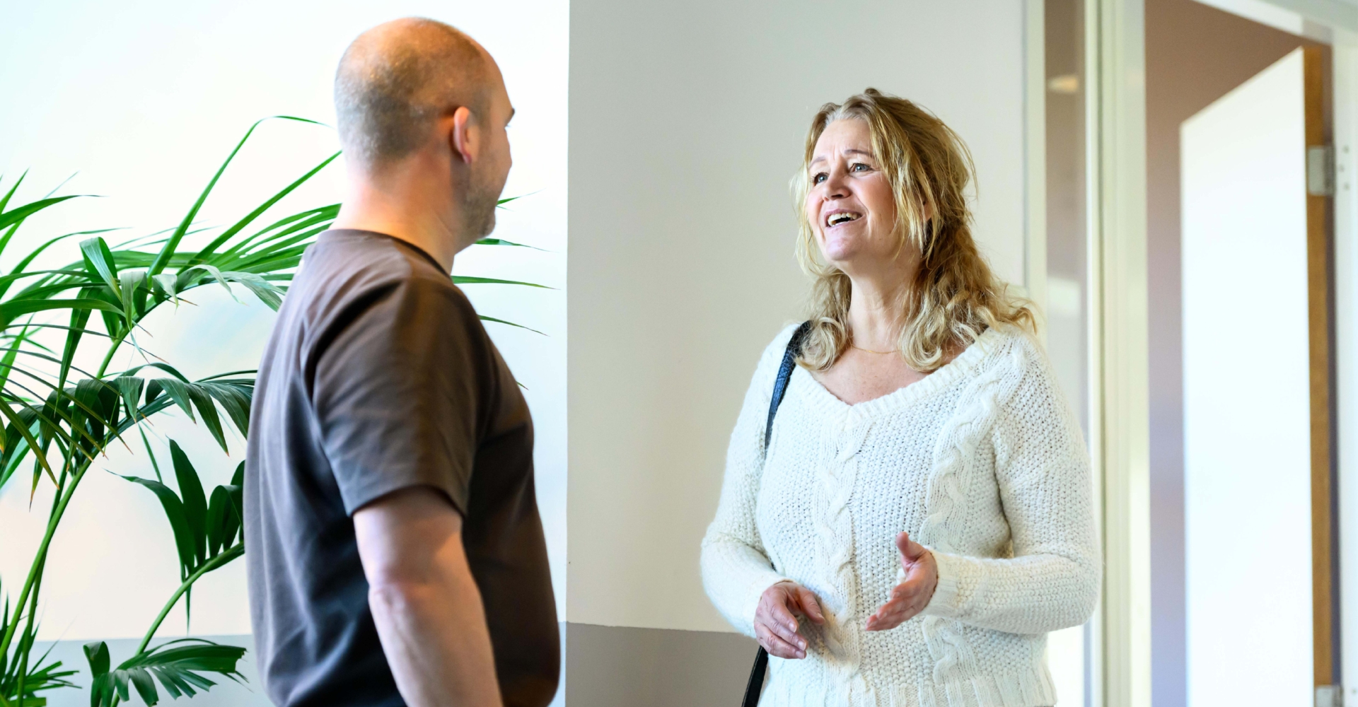 Twee collega's komen elkaar op de gang tegen en praten met elkaar