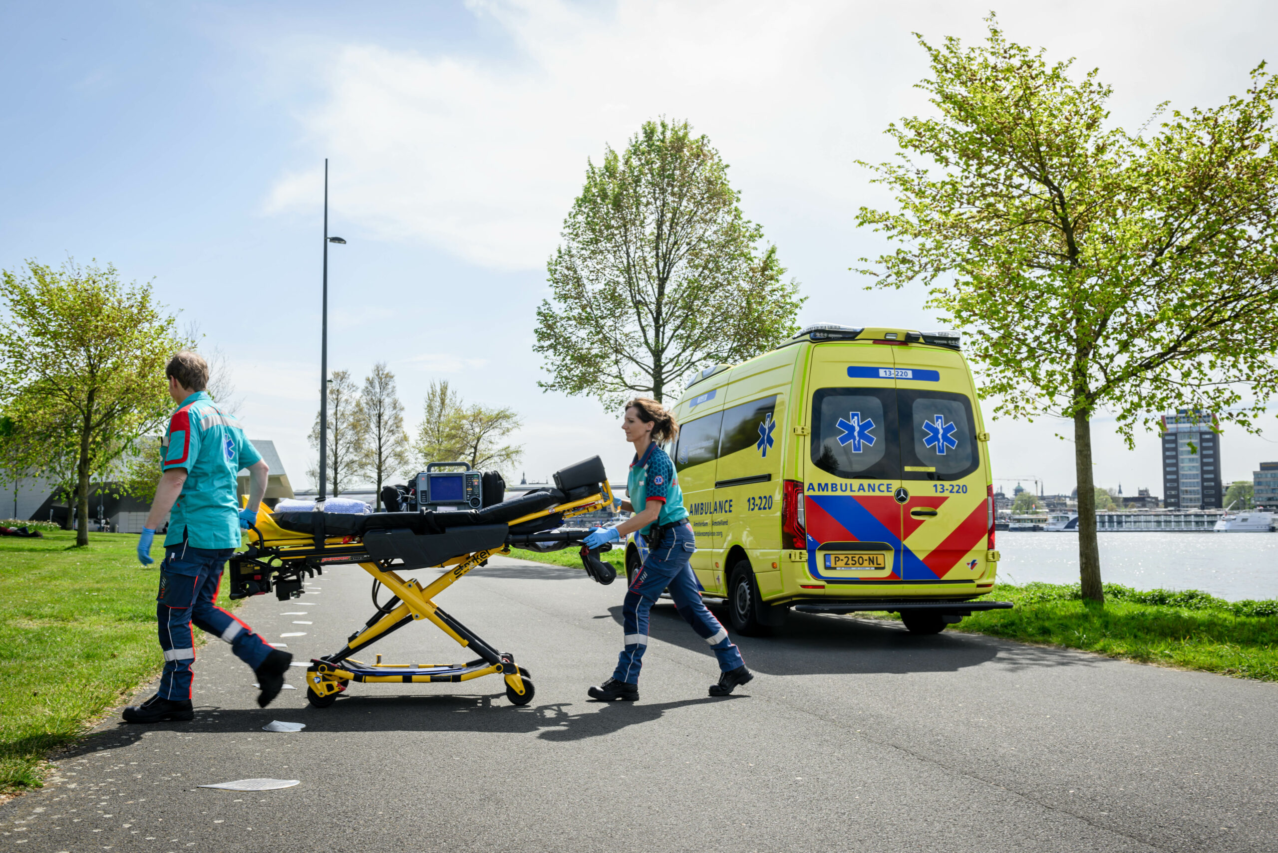 verpleegkundige en chauffeur middencomplexe ambulancelopen buiten met de brancard richting de patiënt