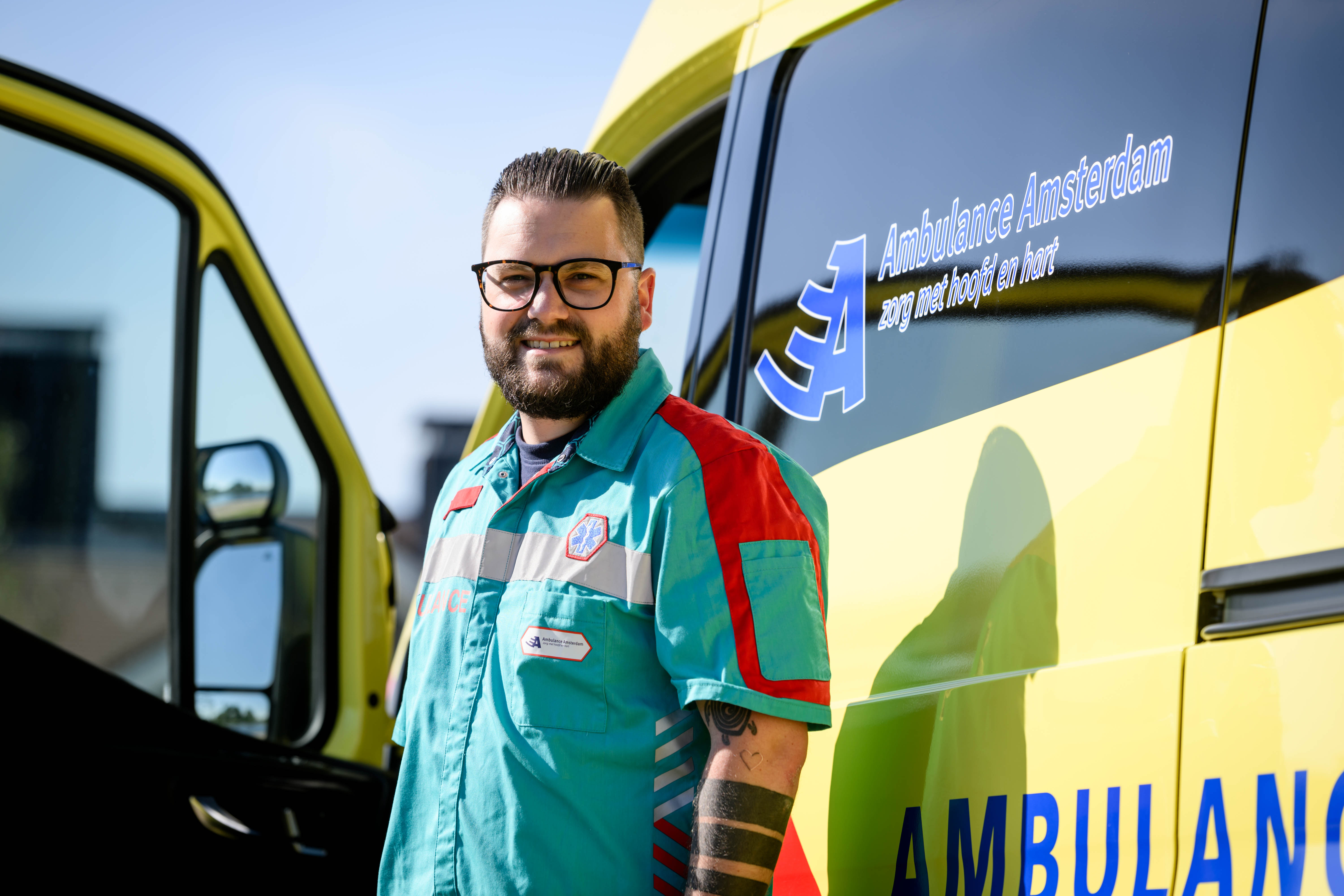 Ambulancechauffeur poseert voor ambulance