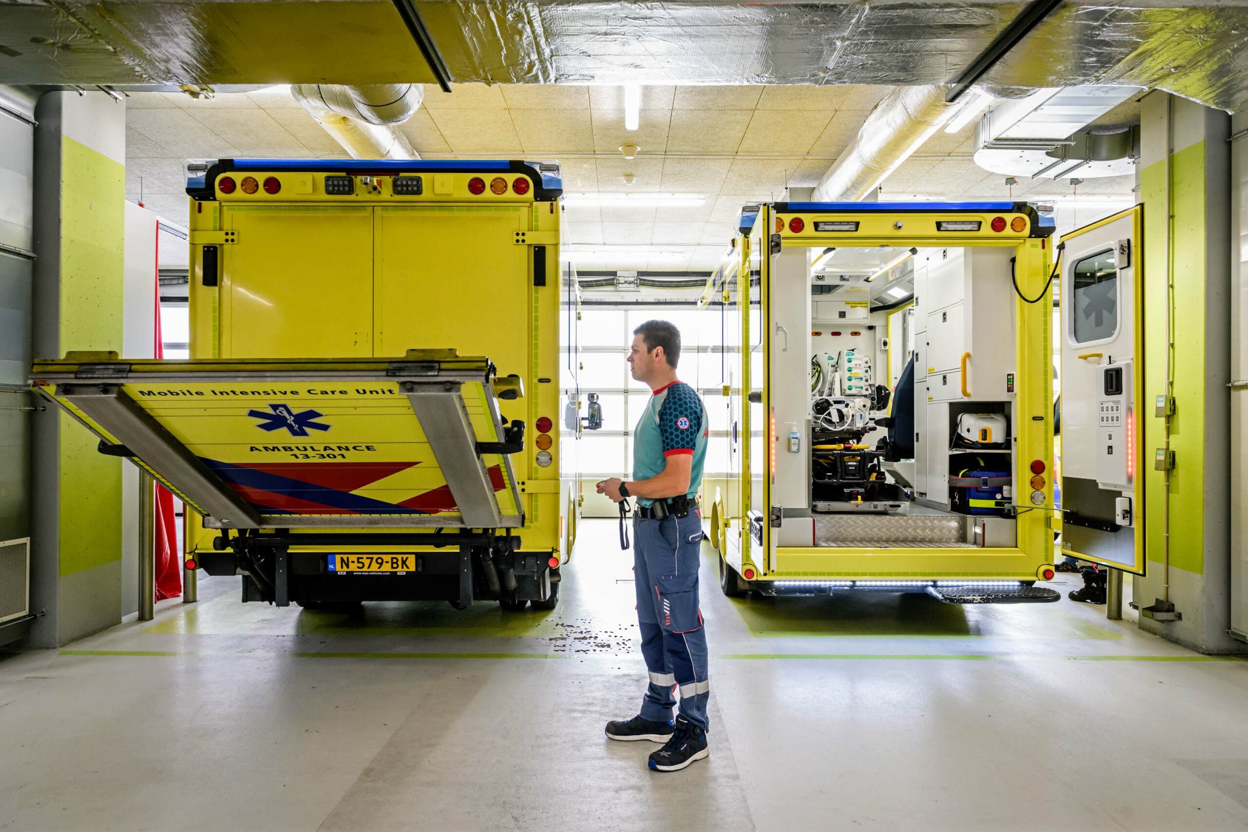 Ambulancechauffeur drukt op een knop om de laadklep van de Mobile Intensive Care Unit (MICU) te laten zakken