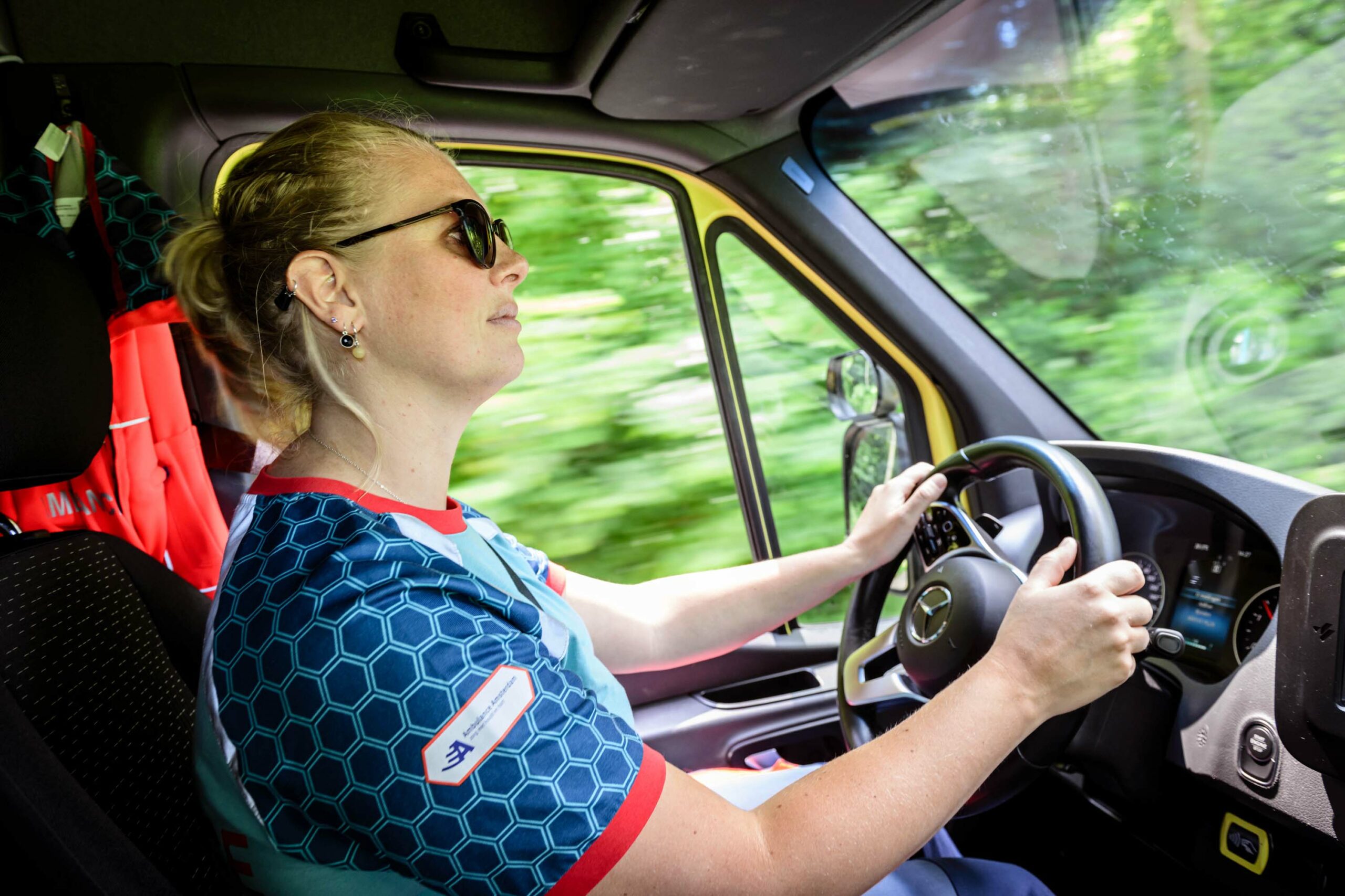 Chauffeur middencomplexe ambulance rijdt in ambulance in een bosrijke omgeving