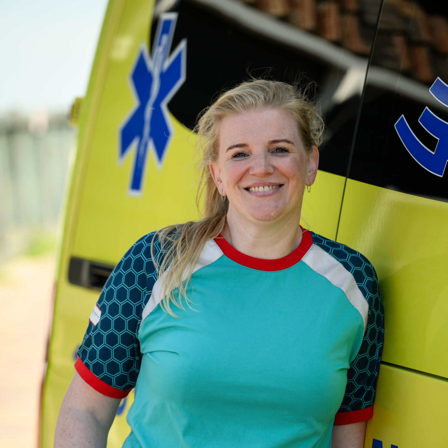 Ambulancechauffeur staat geposeerd naast de ambulance