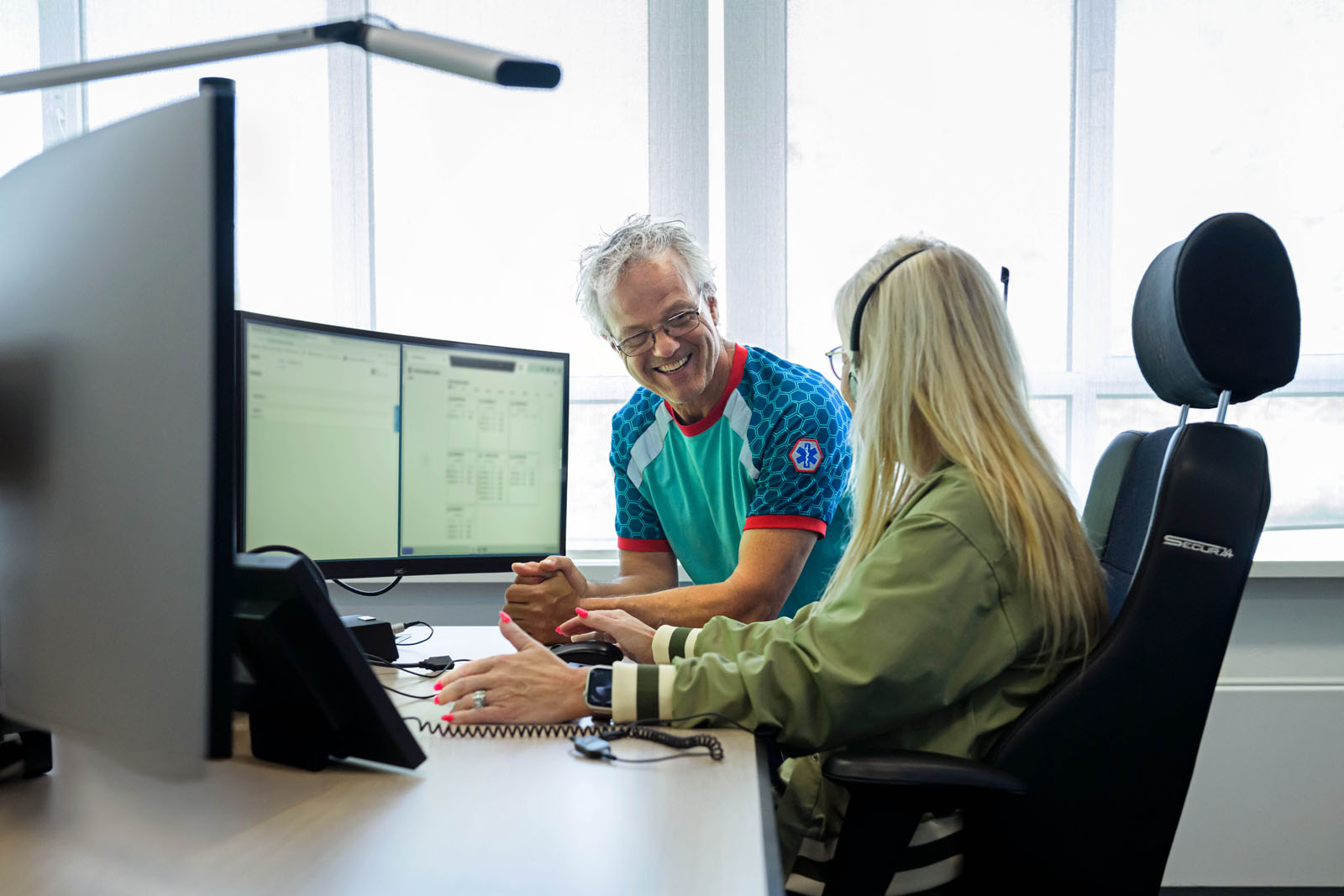 Ambulanceverpleegkundige in gesprek op de meldkamer met meldkamercentralist